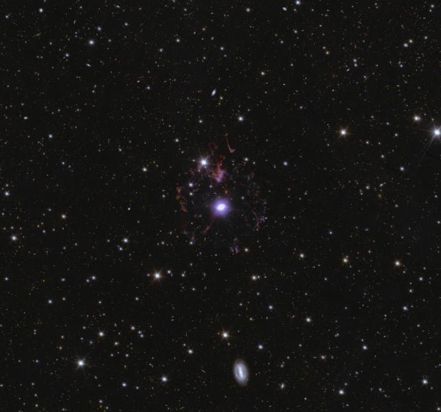 A zoom-in of the Deep Field North shows the Cat's Eye Nebula. The dot in the center is the star, surrounded by loops of gas and dust previously ejected by the star. The background is populated by millions of galaxies